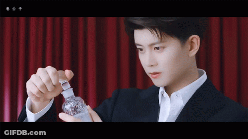 Man In Suit Holding Small Bottle GIF