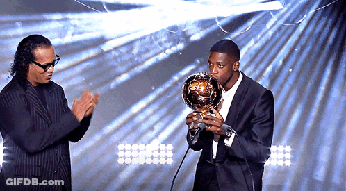 Man In Suit Holding Trophy At Microphone GIF