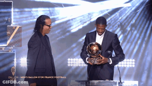 Man In Suit Holding Trophy At Microphone Saying Ballon D'Or GIF