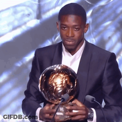Man In Suit Holding Trophy At Microphones GIF