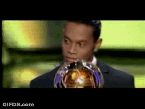 Man In Suit Holding Trophy In Front Of Face GIF
