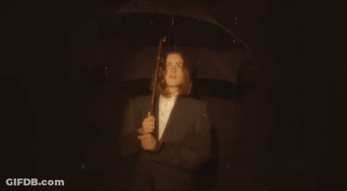 Man In Suit Holding Umbrella In Rain GIF