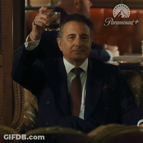 Man In Suit Holding Whiskey In Front Of Paramount Sign GIF