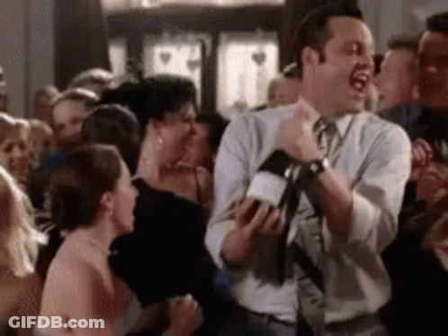 Man In Suit Holding Wine In Front Of Crowd GIF