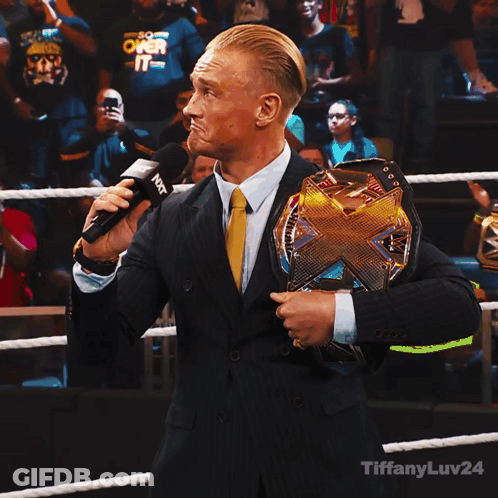 Man In Suit Holding Wrestling Championship Belt Talking Into Microphone GIF