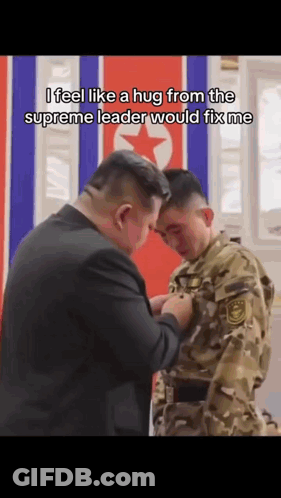 Man In Suit Hugging Man In Military Uniform In Front Of Flag GIF