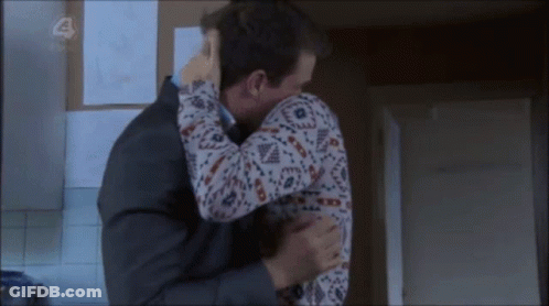 Man In Suit Hugging Woman In Sweater With Number 4 GIF