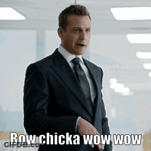 Man In Suit In Front Of Bow Chicka Wow Wow Sign GIF
