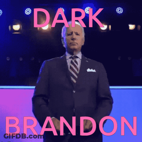 Man In Suit In Front Of Dark Brandon Sign GIF