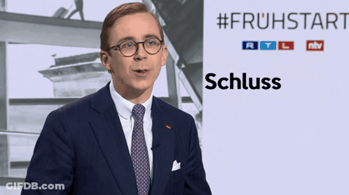 Man In Suit In Front Of #Frühstart Sign GIF