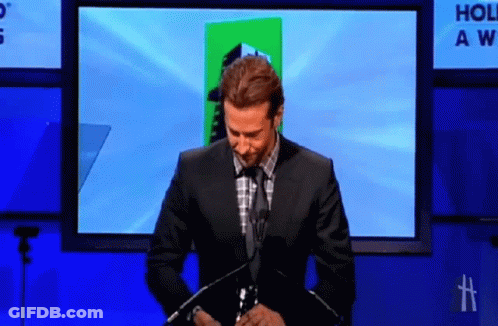 Man In Suit In Front Of Hollywood Awards Screen GIF