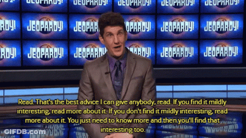 Man In Suit In Front Of Jeopardy Signs GIF