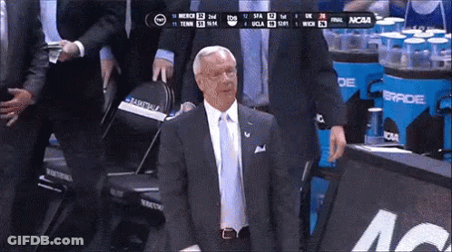 Man In Suit In Front Of NCAA Scoreboard GIF