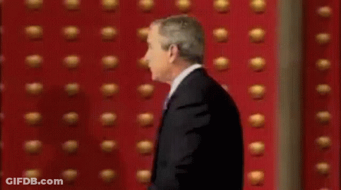 Man In Suit In Front Of Red Wall GIF