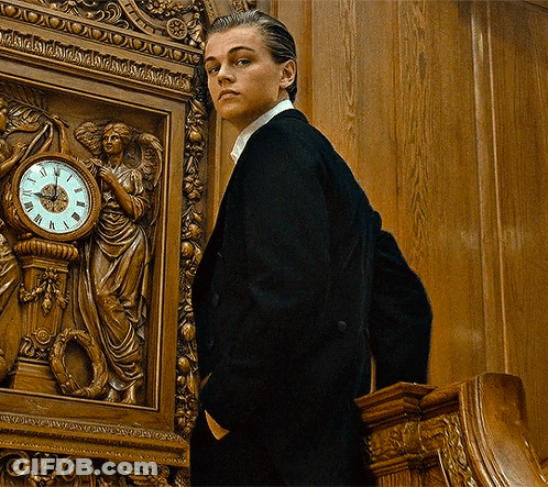 Man In Suit In Front Of Roman Numeral Clock GIF