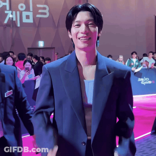 Man In Suit In Front Of Squid Game 3 Sign GIF