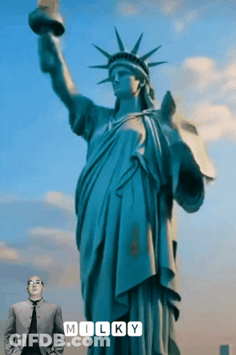 Man In Suit In Front Of Statue Of Liberty Saying Milky GIF