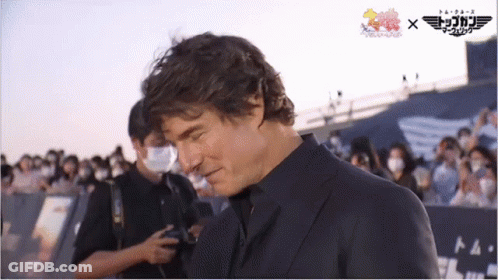 Man In Suit In Front Of Top Gun Sign GIF