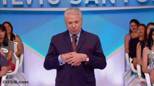Man In Suit In Front Of TVio Santos Sign GIF