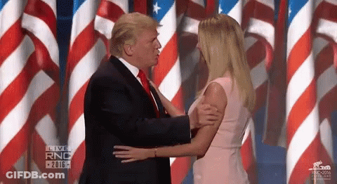 Man In Suit Kissing Woman In Pink Dress On Stage With American Flags GIF