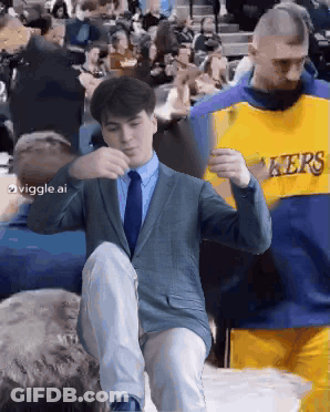 Man In Suit Kneeling Next To Lakers Jersey GIF