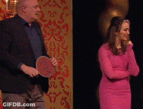 Man In Suit Kneeling Next To Woman In Pink Shirt GIF