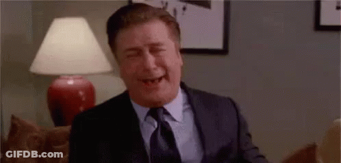 Man In Suit Laughing Eyes Closed On Couch GIF
