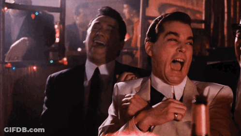 Man In Suit Laughing While Another Man Looks On GIF