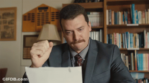 Man In Suit Looking At Paper With Fist In Air GIF
