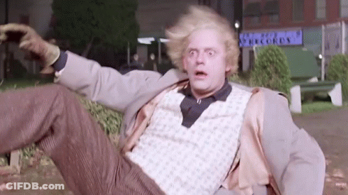 Man In Suit Lying In Park With Arms Outstretched GIF