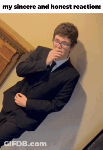 Man In Suit Lying On Wall With Hand To Mouth GIF