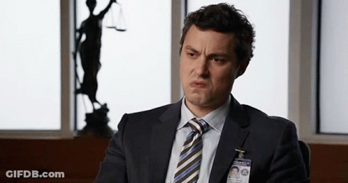Man In Suit Making Funny Face At Justice Statue GIF