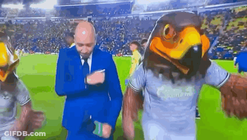 Man In Suit Next To Eagle Head Mascot GIF