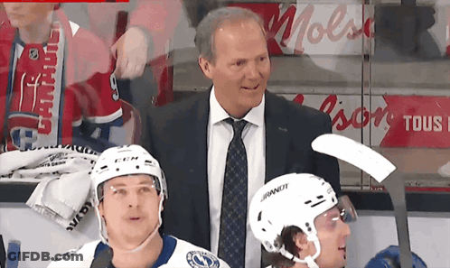 Man In Suit Next To Hockey Player Wearing Bauer Helmet GIF