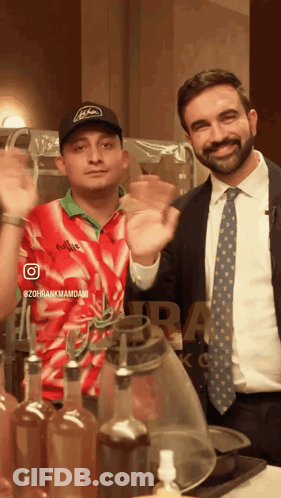 Man In Suit Next To Man In Red And White Emirates Shirt GIF
