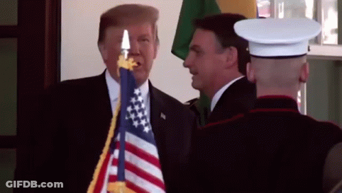 Man In Suit Next To Man In Uniform Holding American Flag GIF