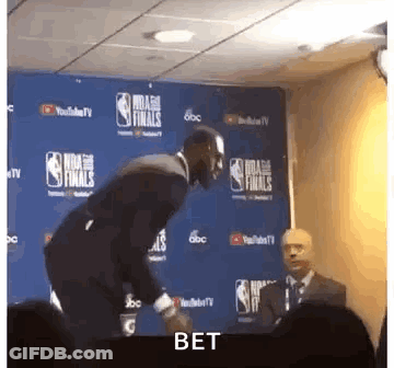 Man In Suit Next To NBA Finals Sign GIF