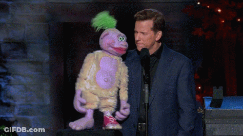 Man In Suit Next To Purple Puppet With Green Mohawk GIF