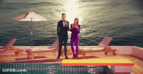 Man In Suit Next To Woman In Purple Pants GIF
