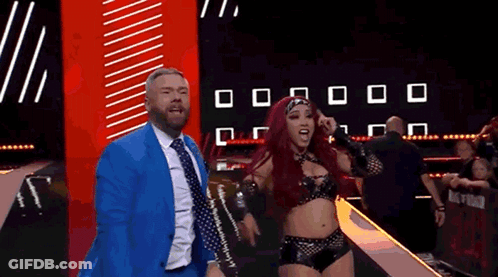 Man In Suit Next To Woman In Wrestling Costume GIF
