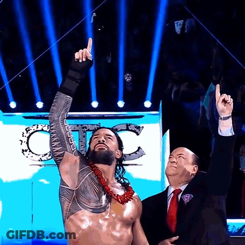 Man In Suit Next To Wrestler Pointing Up GIF