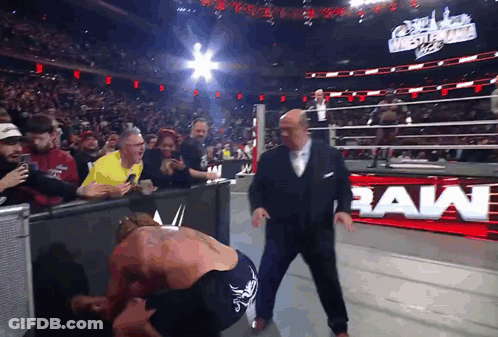 Man In Suit Next To Wrestler With Raw Sign GIF