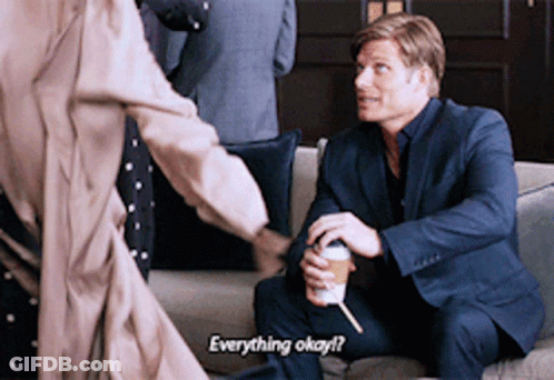 Man In Suit On Couch Talking To Man Holding Coffee GIF