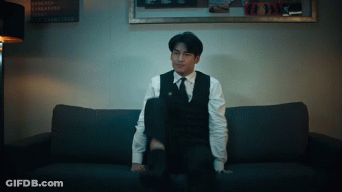 Man In Suit On Couch With Bangkok Singapore Dubai Sign GIF