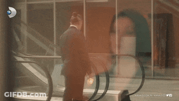 Man In Suit On Escalator In Front Of Kanal.com.tr Building GIF