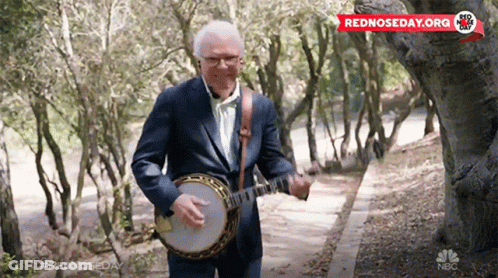 Man In Suit Playing Banjo In Woods Sponsored By NBC GIF