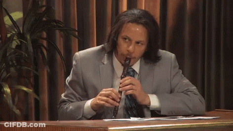 Man In Suit Playing Flute At Desk GIF