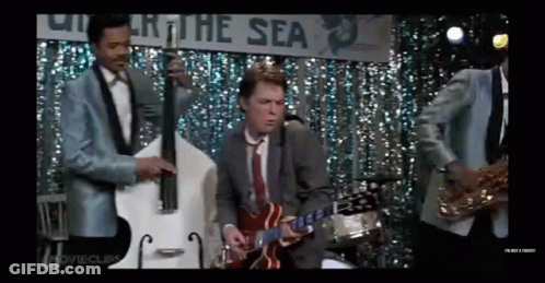 Man In Suit Playing Guitar On Stage With Band GIF