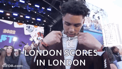 Man In Suit Putting On Chain London Scores GIF