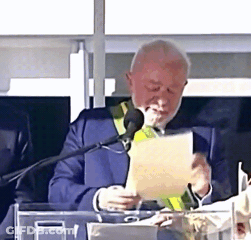 Man In Suit Reading Paper At Microphone GIF
